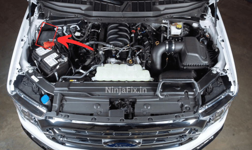Pic of ford f150 engine bay to with red circle and arrow to showcase the location of under hood fuse box location in 2023 ford f 150