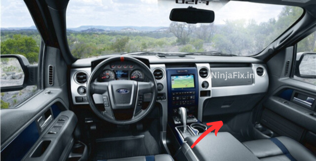 an image of the Ford F-150 dashboard with read box and arrow to highlights the fuse box of passenger compartment to demonstrate the location of AC fuse box location .